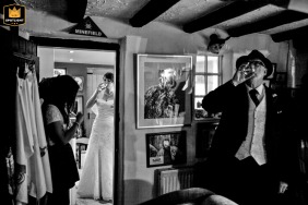 Captured in Cheshire, England, this black and white picture at a family home captures a poignant moment before the bride and her father head to the church, sharing a glass of champagne, reflecting a sentimental pre-wedding scene full of love.